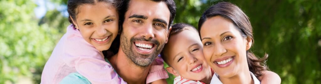 Family Dentistry - San Marcos Portrait of parents and children smiling together at the park